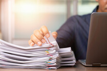 Businessman Hand Pick Up Stack Overload Documents Report Paper With Colorful Paperclip With Fair Light To Analyze Data