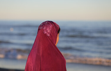 Wall Mural - young woman with arabic veil on her head by the sea