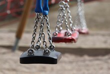 Empty Colorful Swings In School Yeard On A Sunny Day. Concepts Of Childhood And Play.  Selective Focus.