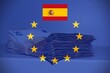 © RafMaster - Pile of fifty euros on the table with the European Flag and the Spanish Flag, concept of financial help to Spain