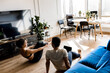 © shunevich - Back view couple stretching watching fitness video tutorial online on laptop. Fit man and woman doing yoga workout at home sitting on floor in living room together, hold hands.