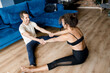 © shunevich - Fit woman and man in sportswear doing yoga on floor at home using laptop holding tutorial,waving hello to students.Female male coaches have a virtual yoga class on computer.Active lifestyle concept.