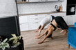 © shunevich - Couple exercising together on the modern kitchen floor. Man and woman in sports wear doing workout at home. Caring girl helping her boyfriend to do stretching