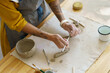 © DimaBerlin - Female ceramist making pottery cup in studio, closeup shot. Creative woman pottery master with tattoo on hands shaping pot mug of wet clay at table. Craftsmanship and art hobby entertainment concept