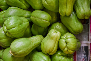 Green chayotes placed on a shelf for sale inside a market