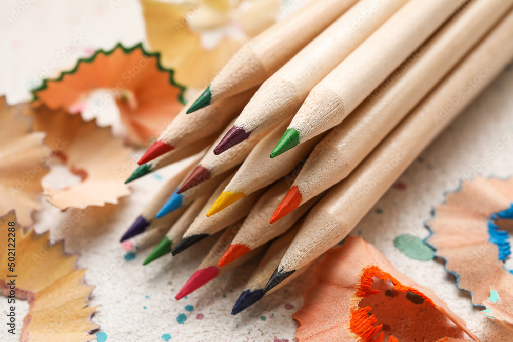 Colorful pencils and shavings on light grunge background