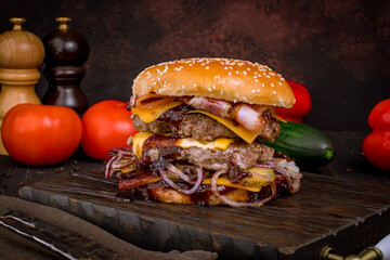 Wall Mural - Burger with double meat patty, bacon, cheese and red onion on bbq sauce on dark stone table