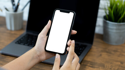 Wall Mural - Hands of a woman using a  smartphone mockup at his desk. Mobile phone blank screen for editing graphics.