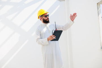 Wall Mural - working on tablet and walkie talkie. Arab man Construction civil engineer use digital tablet computer and wearing in safety hard hat helmet working on Building Site.