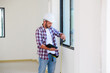© NVB Stocker - Man installing windows in  new house construction site. Hispanic Construction worker wearing protect gloves and hardhat helmet