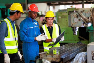 Wall Mural - Training trainee concept. Yang male african american engineer explain the procedure for using the correct metal machine look at online  manual in laptop at factory.