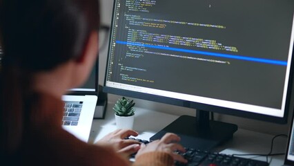 Wall Mural - Young Asian woman, developer programmer, software engineer, IT support, wearing glasses working hard at night overtime on computer to check coding in bugging system. Back view