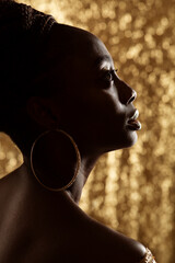 Wall Mural - African Woman Face Profile Black Silhouette with Large Golden Rings Earrings. Dark Skinned Beauty Model with Gold Jewelry over shining Bokeh Background looking up