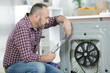 © auremar - serviceman repairing washing machine looking at tablet