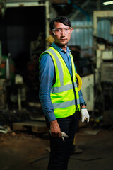 Wall Mural - Portrait Asian man worker look at camera. Metal machine in heavy Industry Manufacturing. Asian male factory worker wearing safety hard hat helmet