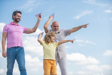 Wall Mural - Active family leisure with kids. Boy son with father and grandfather with a toy airplane plays on summer sky background.