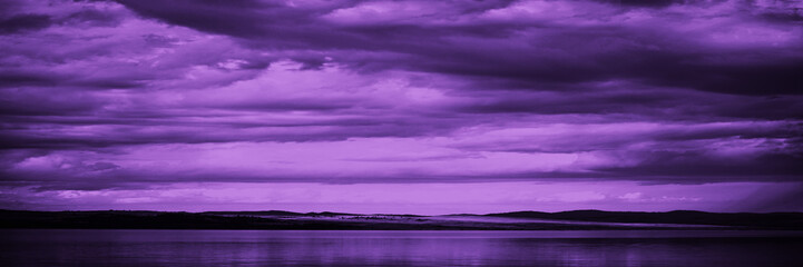 Wall Mural - purple sunset. sky with clouds over the sea. dramatic. mountains on the horizon. beautiful toned lan