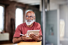 Thoughtful Man With Digitized Pen And Tablet Computer At Home