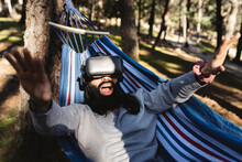 Man With Mouth Open Wearing Virtual Reality Simulator Gesturing Lying In Hammock
