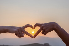 Silhouette Hands In Heart Shape On Mountain Outdoors In Summer Park At Sunset