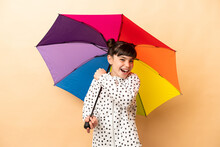 Little Girl Holding An Umbrella Isolated On Beige Background Celebrating A Victory