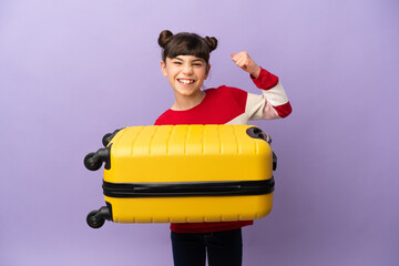 Wall Mural - Little caucasian girl isolated on purple background in vacation with travel suitcase