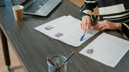 Wall Mural - Office worker analyzing candidates cv and application form before attending job interview and hiring people. Recruiter searching on papers for person with business expertise. Close up.