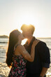 © Westend61 - Young couple kissing each other in front of sea on sunny day