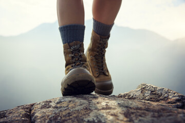 Wall Mural - suceesful woman hiker legs stand on mountain peak cliff edge