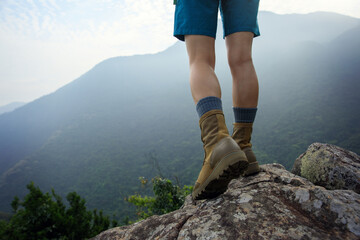Wall Mural - suceesful woman hiker legs stand on mountain peak cliff edge