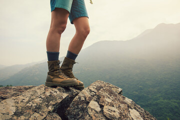 Wall Mural - suceesful woman hiker legs stand on mountain peak cliff edge