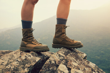 Wall Mural - suceesful woman hiker legs stand on mountain peak cliff edge
