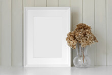 Empty Picture Frame With Beautiful Bouquet Of Dried Hydrangea Flowers. Modern White Ceramic Vase With Dry Grass. Wooden Wall Background. Elegant Scandinavian Interior. Summer, Fall Still Life Photo
