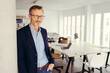 © contrastwerkstatt - businessman standing in modern office wearing glasses and looking to the side