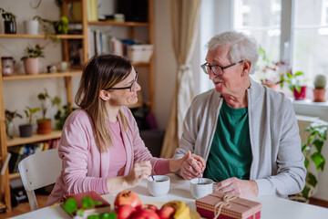 Wall Mural - Adult daughter visiting her senior father at home and having coffee together, talking.