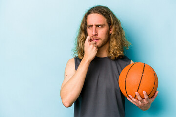 Wall Mural - Young caucasian man playing basketball isolated on blue background relaxed thinking about something looking at a copy space.