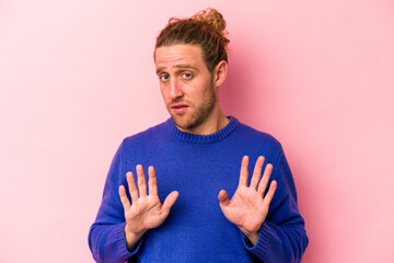 Young caucasian man isolated on pink background rejecting someone showing a gesture of disgust.