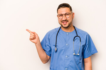 Wall Mural - Hispanic nurse man isolated on white background smiling and pointing aside, showing something at blank space.