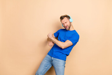 Poster - Photo of young excited man good mood clubber chill sound mp3 hang-out isolated over beige color background