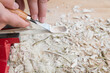 Selbst geschnitzter Holzlöffel eingespannt im Schraubstock bearbeitet mit Messer Werkzeug auf einer Werkbank mit Holzspäne, Deutschland