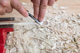 Fototapeta  - Selbst geschnitzter Holzlöffel eingespannt im Schraubstock bearbeitet mit Messer Werkzeug auf einer Werkbank mit Holzspäne, Deutschland