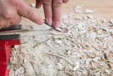 Fototapeta  - Selbst geschnitzter Holzlöffel eingespannt im Schraubstock bearbeitet mit Messer Werkzeug auf einer Werkbank mit Holzspäne, Deutschland