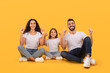 © Prostock-studio - Cheerful Arabic Family Pointing Fingers Up Sitting Over Yellow Background