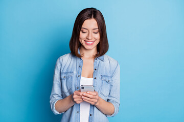Wall Mural - photo of pretty cute woman wear jeans shirt communicating modern device isolated blue color backgrou