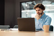 © Prostock-studio - Focused man using laptop sitting at desk in office
