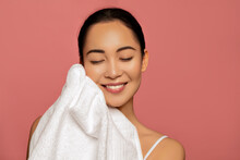 Clean and fresh skin. Beauty portrait of Asian model drying her face with pure white towel. Body care concept