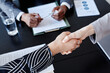 © Seventyfour - Top view closeup of two business women shaking hands over meeting table, copy space