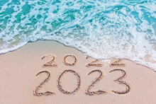 Message Year 2022 Replaced By 2023 Written On Beach Sand Background. Good Bye 2022 Hello To 2023 Happy New Year Coming Concept.

