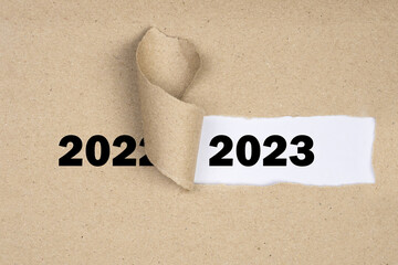 Message Year 2022 replaced by 2023 torn craft paper texture background.
Good bye 2022 hello to 2023 happy New Year coming concept.