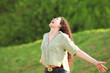 Happy woman screaming in a park outstretching arms